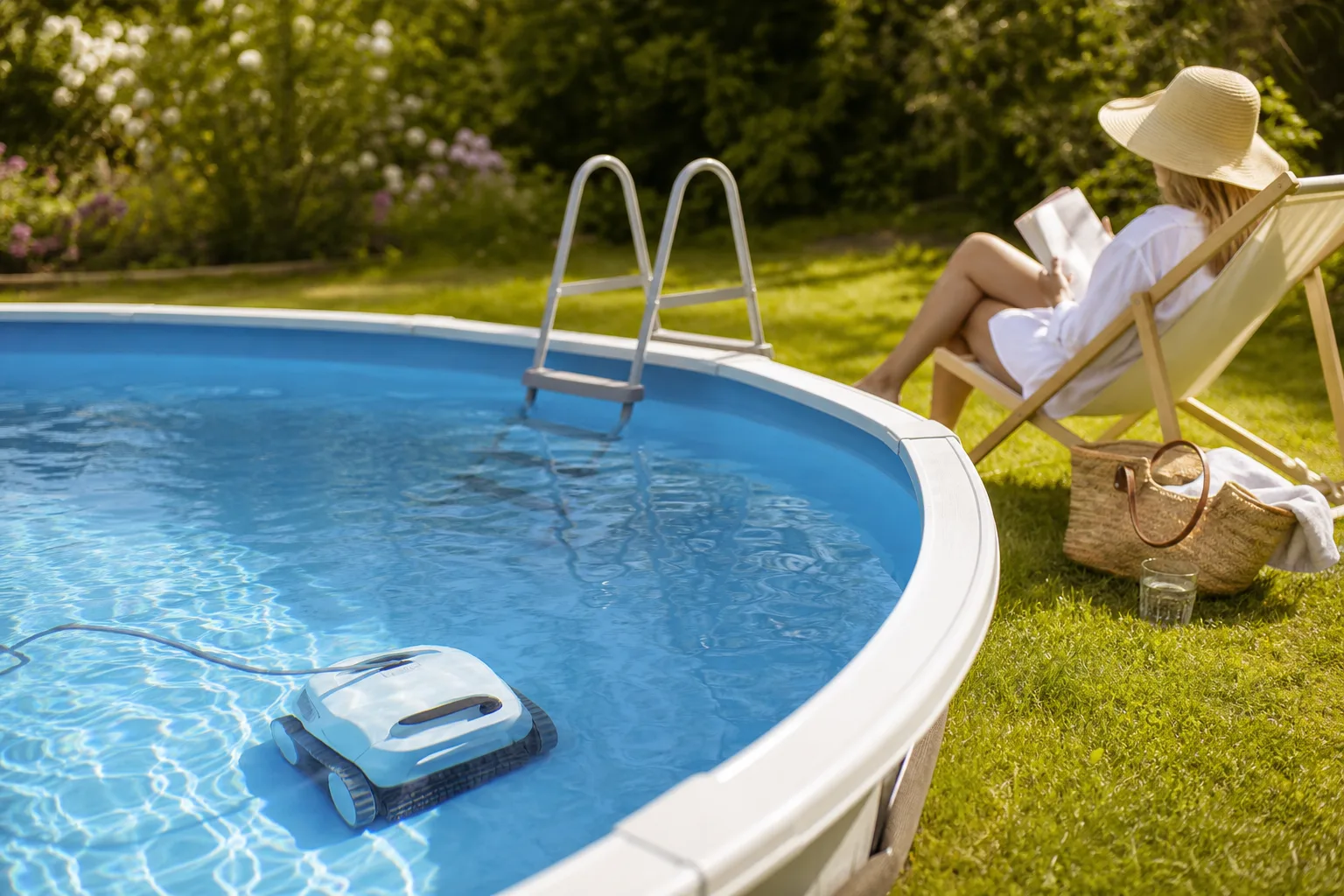Poolrobot rensar botten av en ovanmarkspool i en svensk trädgård medan ägaren kopplar av bredvid